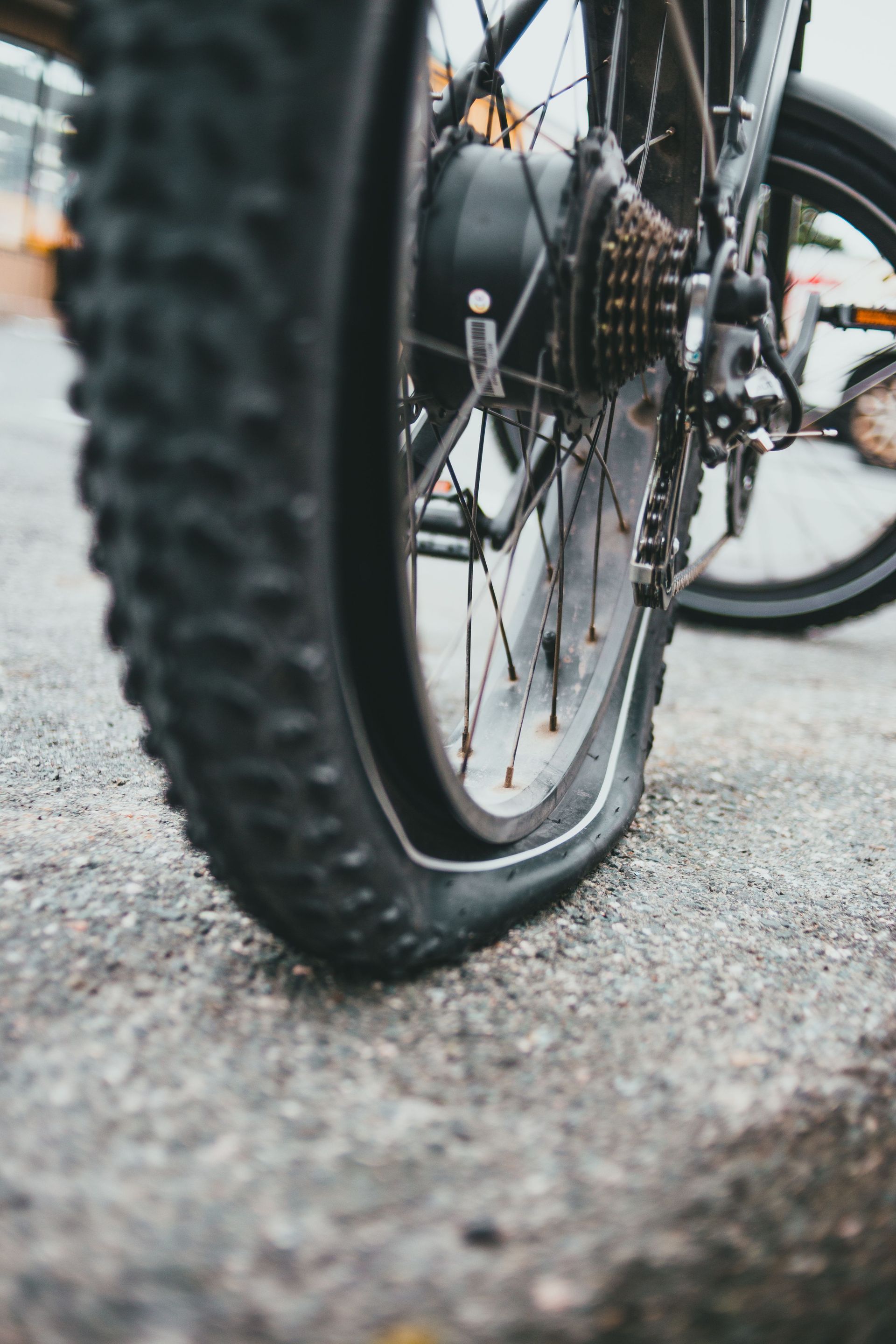Detailed view of a bicycle wheel with a flat tire on a road surface.